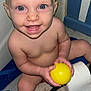 baby, child, smiling, blue_eyes, yellow_ball, toilet_paper, purple_object, rug, indoor, curtain, wall, person, skin, hand, foot, face, sitting, happy, playing, toddler