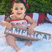 Gabriella joined the competition — help win amazing prizes! accessories, baby, beachwear, bodypart, clothing, dress, face, finger, flag, hand, happy, head, laughing, person, photography, portrait, sitting, smile, summer, swimwear