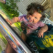 Analaya is registered to the contest to win money with this photo: baby, child, curly_hair, smile, car_window, reflection, hand, adult, shirt, outdoor, greenery, house, sunlight, keys, window, face, person, happy, playful, closeup