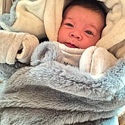 Emile participe au concours pour gagner de l'argent avec cette photo : airbag_label, baby, blanket, car_seat, closeup, cozy, cute, eyes, face, fur_blanket, hood, indoor, infant, mittens, plush, portrait, smiling, soft_texture, swaddle, warm