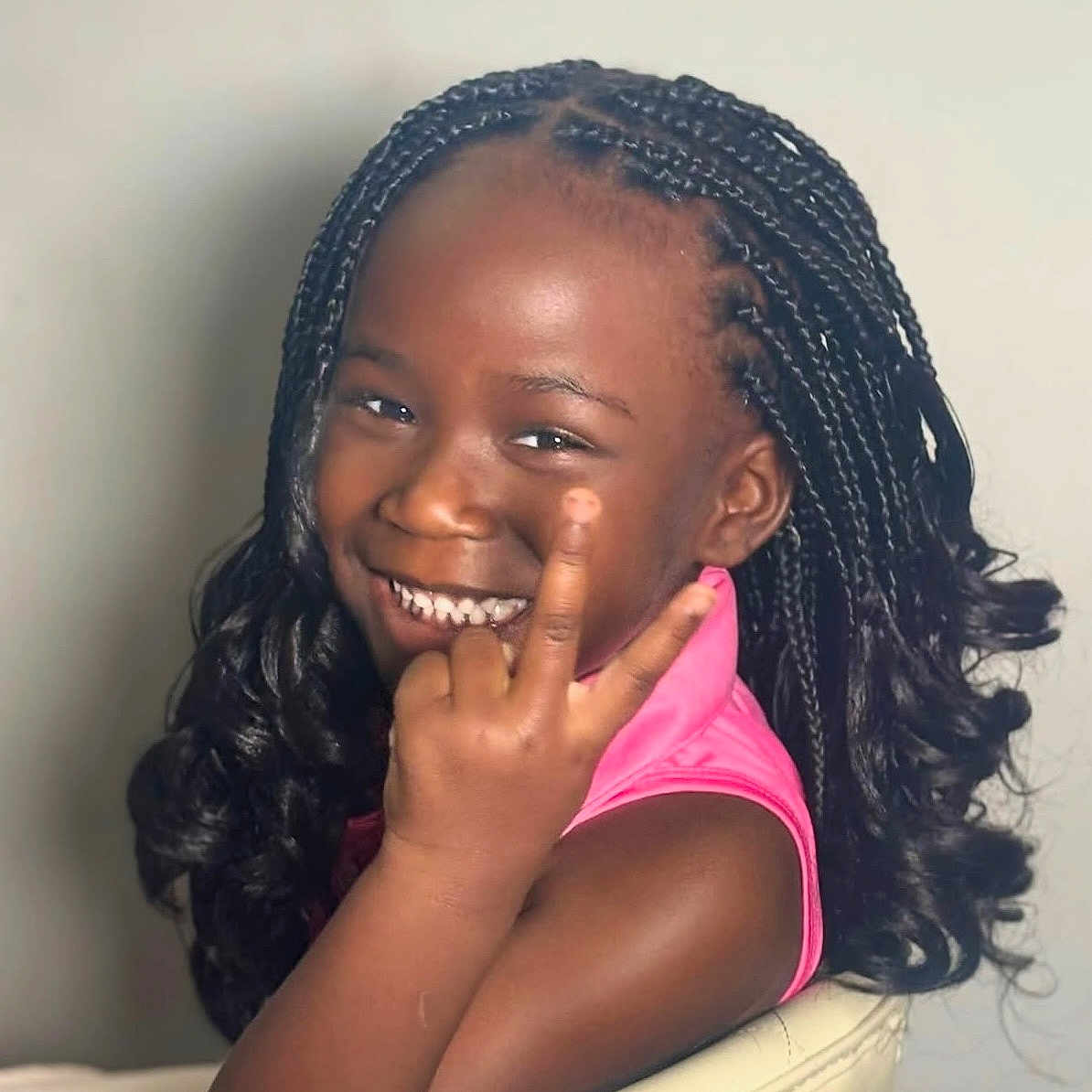 Wynter is registered to the contest to win money with this photo: black_hair, braided_hair, casual, chair, child, curly_hair, cute, dark_skin, face, girl, hand_gesture, happy, indoor, peace_sign, person, pink_clothing, portrait, seated, smile, young