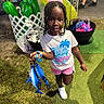 Wynter is registered to the contest to win money with this photo: artificial_turf, braided_hair, carnival, child, fair, girl, grass, hand, net, outdoor, person, pink_bow, play, prizes, shark, shorts, smile, sneakers, toy, tshirt