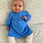 Lya a rejoint le concours — aidez-le/la à gagner de superbes lots ! baby, blanket, blue_dress, bright_eyes, child, clothing, cozy, cute, face, grin, happy, indoors, infant, patterned_blanket, person, portrait, sitting, smiling, white_socks, young_child