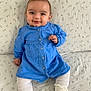 baby, blanket, blue_dress, bright_eyes, child, clothing, cozy, cute, face, grin, happy, indoors, infant, patterned_blanket, person, portrait, sitting, smiling, white_socks, young_child