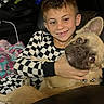 blanket, boy, brown_dog, casual, checkered_clothing, child, couch, cozy, dog, domestic_animal, face, french_bulldog, happy, hugging, indoor, leather_furniture, pet, portrait, smiling, young_child
