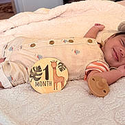 Audi joined the competition — help win amazing prizes! baby, infant, smiling, sleeping, blanket, pacifier, clothing, hat, wooden_sign, giraffe, one_month, cute, resting, newborn, soft_texture, indoor, portrait, milestone, child, peaceful