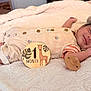 baby, infant, smiling, sleeping, blanket, pacifier, clothing, hat, wooden_sign, giraffe, one_month, cute, resting, newborn, soft_texture, indoor, portrait, milestone, child, peaceful
