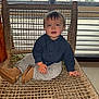 Orso participe au concours pour gagner de l'argent avec cette photo : child, toddler, baby, sitting, woven_chair, chair, boots, shirt, corduroy_pants, hands, face, smile, hair, indoor, window_blinds, home_interior, portrait, woven_texture, floor, happy