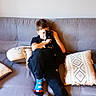 Lolly participe au concours pour gagner de l'argent avec cette photo : boy, cat, couch, gray, home, indoor, pillow, child, sitting, black_cat, casual, relaxing, comfort, wall_art, colorful_socks, snuggling, furniture, cozy, happy, portrait
