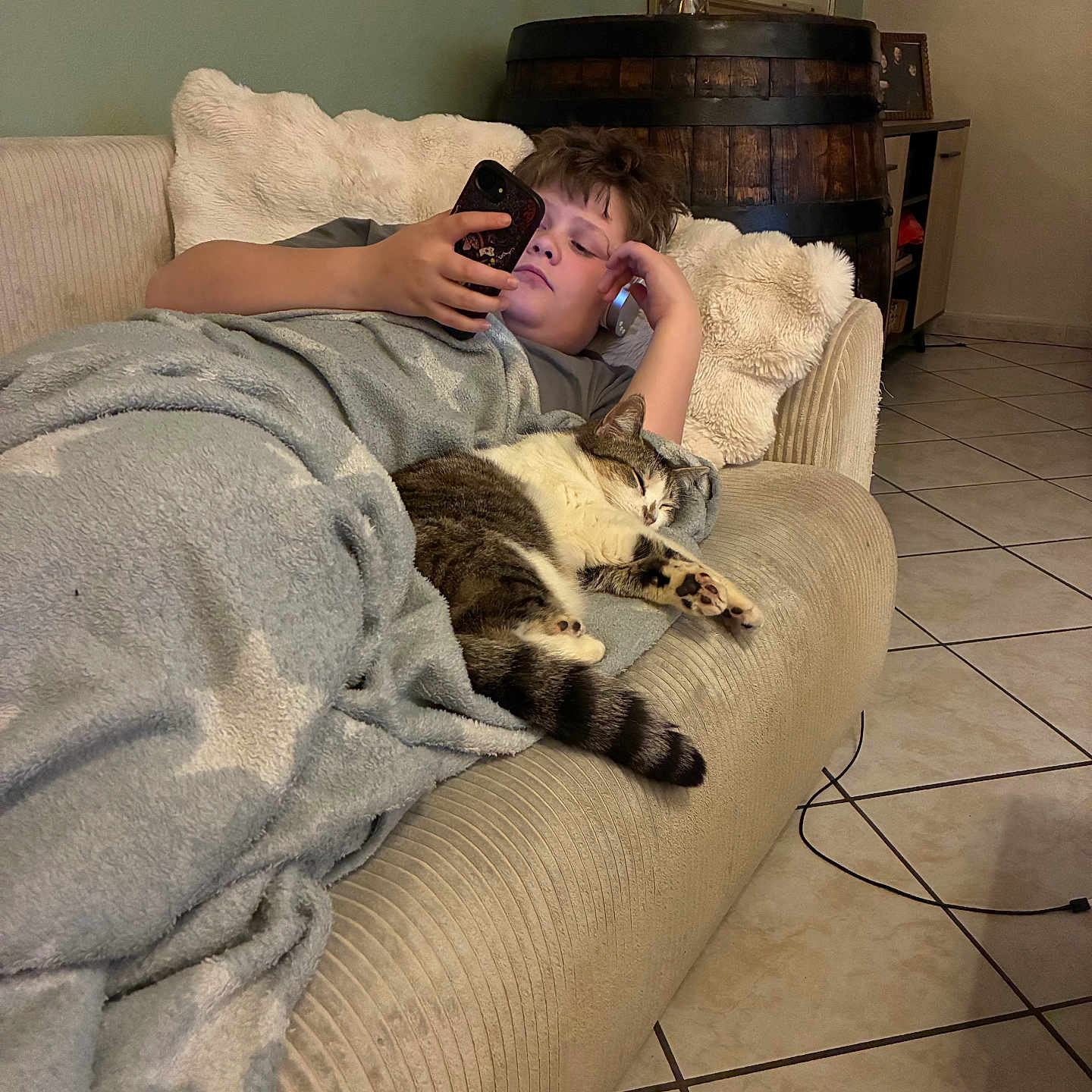 Pop participe au concours pour gagner de l'argent avec cette photo : child, cat, couch, blanket, smartphone, sleeping, indoor, tile_floor, home, relaxing, furniture, cozy, resting, animal, pet, casual, comfort, person, living_room, blanket_with_stars