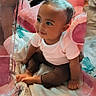 Ailani is registered to the contest to win money with this photo: baby, child, infant, sitting, portrait, smiling, looking_sideways, face, eyes, short_hair, pink_shirt, brown_pants, bare_feet, blanket, bed, cushion, indoor, colorful, cozy, photography