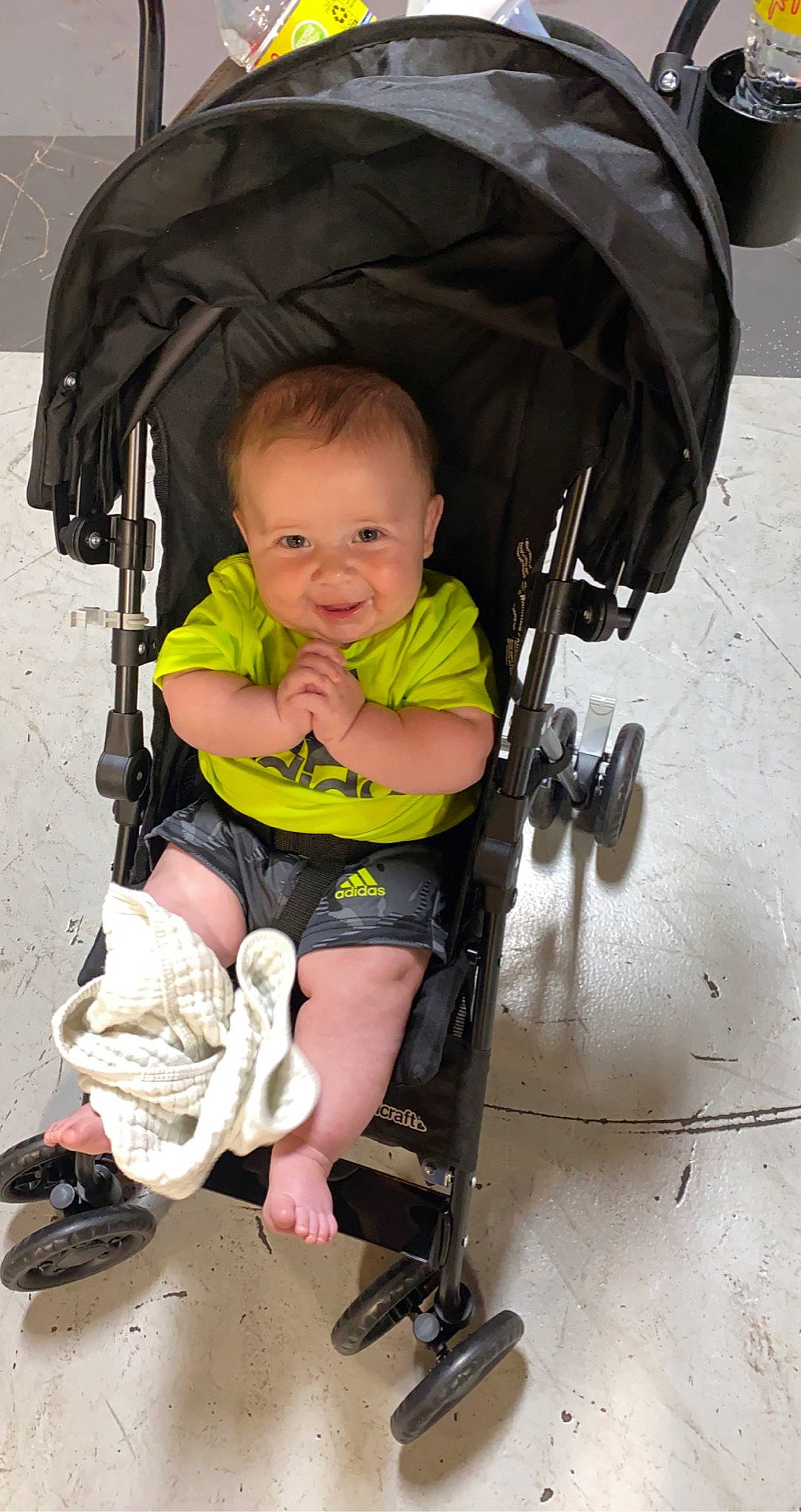 Axton is registered to the contest to win money with this photo: baby, baby_carriage, baby_products, baby_safety, baby_toddler_clothing, beauty, child, comfort, eye, fashion_accessory, fun, head, lap, person, sandal, sitting, smile, tire, toddler, wheel