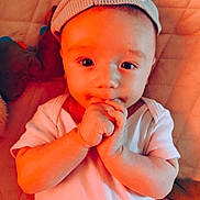 Louie joined the competition — help win amazing prizes! adorable, baby, child, close_up, cute, expression, eyes, face, hands, hat, indoors, infant, knit_hat, lying_down, plush_toys, portrait, quilted_bed, skin, soft_lighting, white_onesie