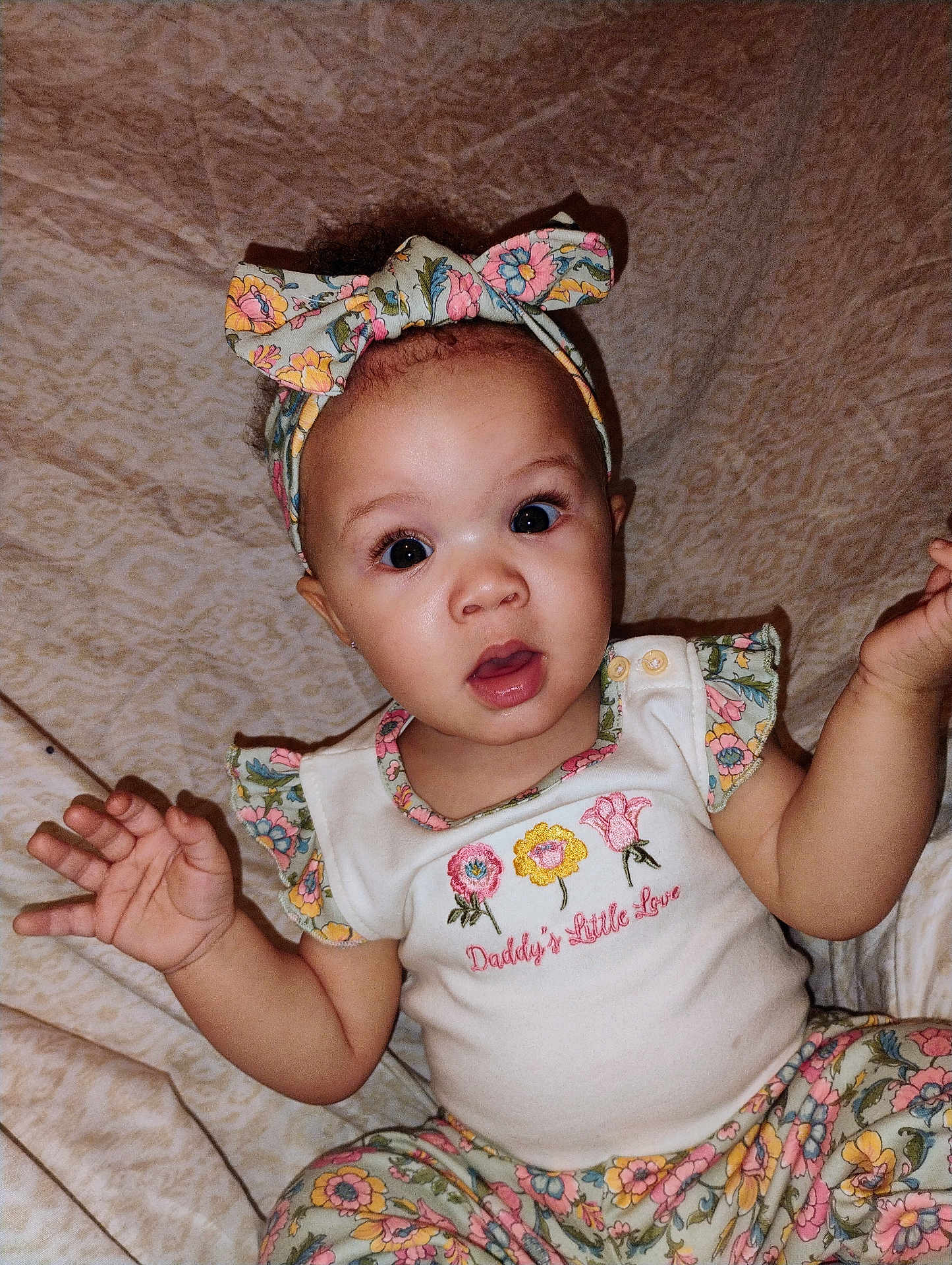 Antania joined the competition — help win amazing prizes! baby, infant, child, headband, bow, floral_pattern, onesie, embroidered_text, big_eyes, surprised_expression, hands, sitting, blanket, indoor, portrait, cute, eyelashes, clothing, mouth_open, patterned_pants