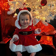 Adalee joined the competition — help win amazing prizes! baby, child, christmas, holiday, festive, red_dress, white_fur, mouse_ears, bow, smile, lights, christmas_tree, ornaments, gifts, wrapped_presents, floor, indoors, happy, cute, portrait