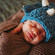 Milo joined the competition — help win amazing prizes! baby, newborn, sleeping, hat, knit_hat, blue_hat, blanket, brown_blanket, swaddle, cozy, portrait, closeup, peaceful, infant, sleeping_baby, adorable, tongue_out, knitted_texture, fabric, newborn_photography