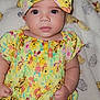 baby, blanket, bow, child, cute, face, hand_fists, headband, indoors, infant, patterned_clothing, portrait, sitting, skin, smiling, soft_toy, teddy_bear_pattern, wide_eyes, yellow_clothing, young