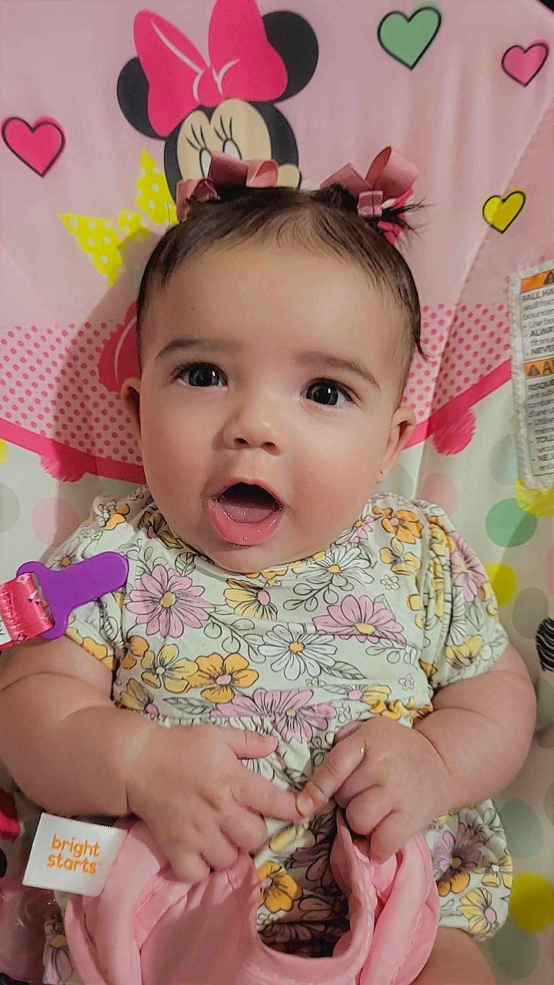 Luna joined the competition — help win amazing prizes! baby, child, infant, pink_bows, floral_dress, minnie_mouse, heart_shapes, baby_seat, cute, wide_eyes, expression, hands, colorful, toy_clip, patterned_clothing, indoor, portrait, happy, small_person, closeup
