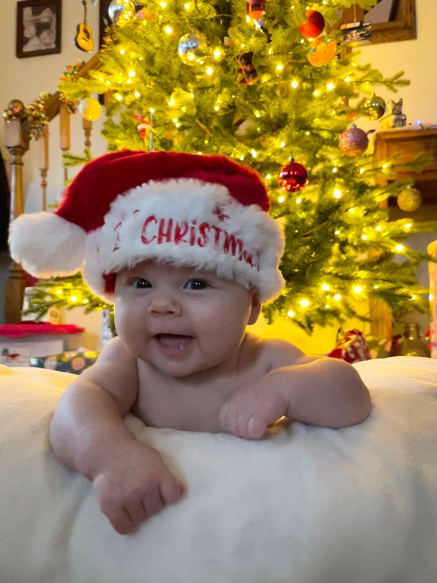 Camilla is registered to the contest to win money with this photo: baby, cap, christmas, christmas_decoration, christmas_ornament, christmas_tree, costume_hat, event, evergreen, eye, happy, headwear, holiday, holiday_ornament, light, ornament, person, plant, smile, toddler