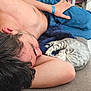 shirtless, young_man, sleeping, kitten, cat, couch, blanket, indoor, relaxing, casual, home, furniture, blue_jeans, bracelet, resting, curled_up, nap, comfort, domestic, cozy