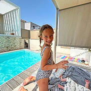 Adèle a rejoint le concours — aidez-le/la à gagner de superbes lots ! child, baby, swimsuit, pool, outdoor, sunny, smiling, blanket, spray_can, deck, shade, modern, playful, summer, water, person, foot, happy, toddler, candid