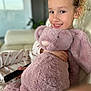 child, smiling, plush_bunny, stuffed_animal, couch, remote_control, pajamas, indoor, happy, portrait, cozy, toy, cute, young, girl, relaxed, home, soft, furniture, person