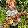 Enver joined the competition — help win amazing prizes! child, curly_hair, smiling, outdoor, forest, wood, mushrooms, greenery, nature, sweater, animal_print, happy, person, holding, plants, grass, shoes, tree_bark, adventure, exploration