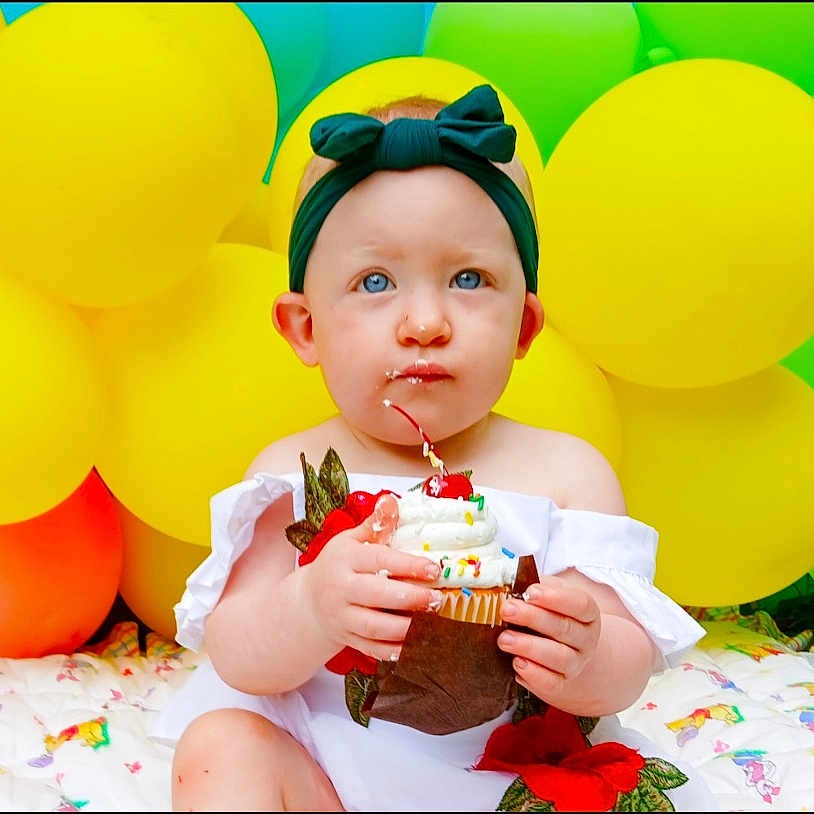 Josie is registered to the contest to win money with this photo: baby, balloon, birthdaycake, bodypart, cake, cream, cupcake, dessert, eating, face, finger, food, fun, hand, head, icecream, icing, party, people, person