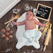 Bradly Mateo joined the competition — help win amazing prizes! baby, baking_utensils, child, chubby, cinnamon_rolls, cooking, cute, expression, flour, food, indoors, infant, kitchen, letter_board, lying_down, measuring_spoons, rolling_pin, white_rug, wooden_floor, wooden_spoons