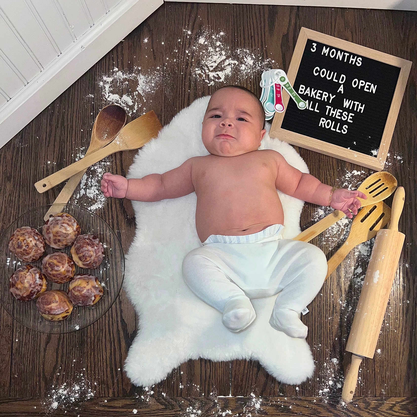 Bradly Mateo joined the competition — help win amazing prizes! baby, baking_utensils, child, chubby, cinnamon_rolls, cooking, cute, expression, flour, food, indoors, infant, kitchen, letter_board, lying_down, measuring_spoons, rolling_pin, white_rug, wooden_floor, wooden_spoons