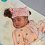 baby, sleeping, pink_clothing, headband, hair_buns, blanket, pacifier, infant, cute, peaceful, soft_lighting, indoors, face, child, pajamas, newborn, resting, floral_pattern, baby_girl, cozy