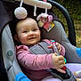 baby, car_seat, toy, pink_clothing, smiling, child, outdoor, greenery, soft_toy, happy, infant, sitting, playful, cute, person, seatbelt, nature, daylight, face, closeup