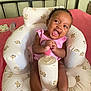 baby, infant, smiling, pink_clothing, seat, teddy_bear_pattern, cushion, bed, bottle, wipes, happy, person, indoor, cute, child, small, skin, feet, hands, head