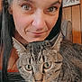 Drew is registered to the contest to win money with this photo: woman, cat, tabby_cat, face, eyes, smile, indoor, portrait, pet, animal, feline, hair, person, closeup, expression, wood_paneling, artwork, curious, snuggling, cozy