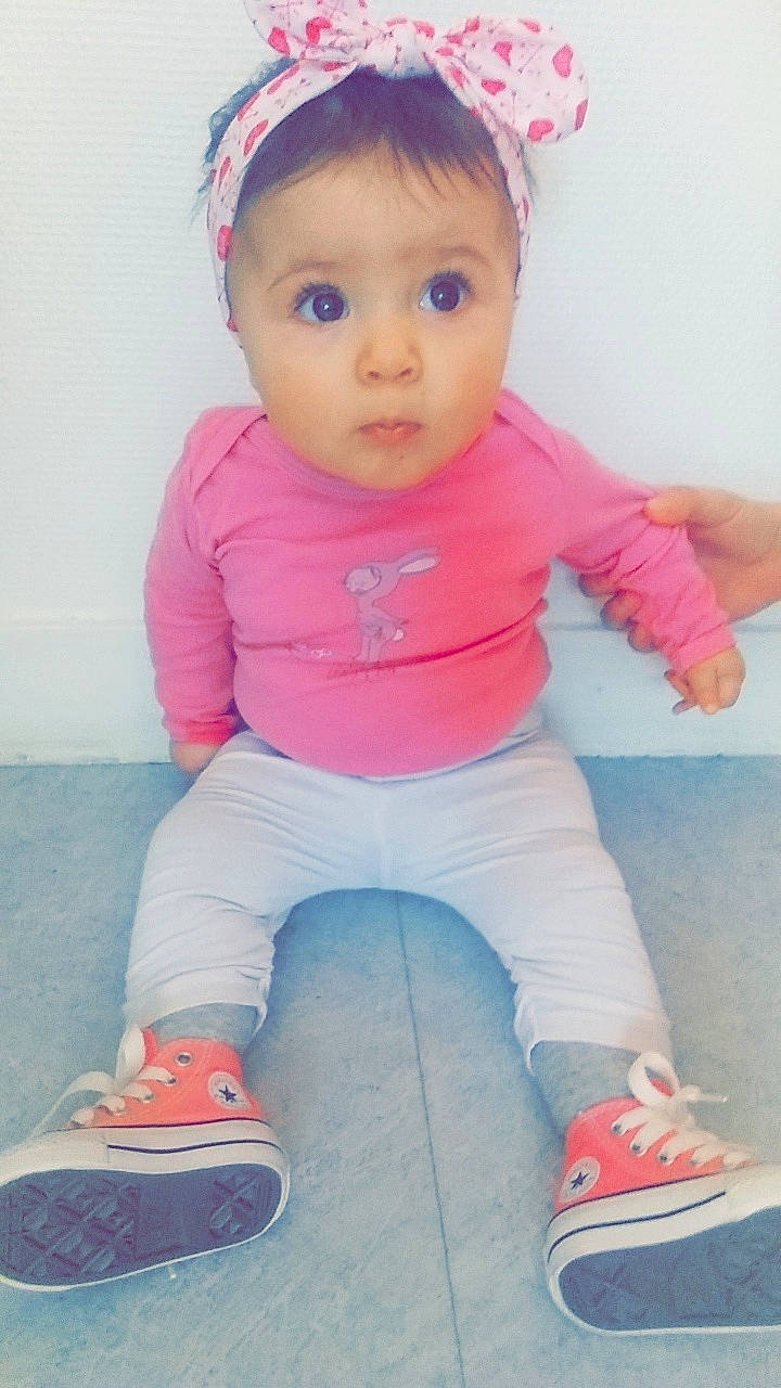 Emy participe au concours pour gagner de l'argent avec cette photo : baby, baby_products, baby_toddler_clothing, cheek, child, hair_accessory, headgear, person, pink, product, skin, smile, standing, surprise, toddler