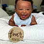 baby, infant, smiling, happy, blue_striped_clothing, white_blanket, wooden_sign, four_months, milestone, portrait, cute, lying_down, indoor, child, face, young, skin, cheerful, closeup, expression