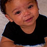 Jayceon is registered to the contest to win money with this photo: baby, child, infant, portrait, smiling, happy, face, curly_hair, black_shirt, white_blanket, indoor, close_up, sitting, hands, eyes, nose, mouth, soft_texture, adorable, photography