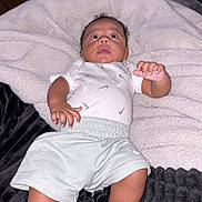 Jayceon is registered to the contest to win money with this photo: baby, infant, child, lying_down, blanket, white_blanket, black_blanket, indoor, portrait, face, wide_eyed, curly_hair, white_shirt, shorts, bare_feet, hands, feet, nursery, household, photography