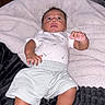 baby, infant, child, lying_down, blanket, white_blanket, black_blanket, indoor, portrait, face, wide_eyed, curly_hair, white_shirt, shorts, bare_feet, hands, feet, nursery, household, photography