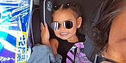 Camila joined the competition — help win amazing prizes! child, sunglasses, car_seat, smile, car_interior, person, packaging, paper_towels, glasses, seat, hair, clothing, window, headrest, seatbelt, vehicle, adult, happy, portrait, interior