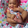 baby, infant, child, smiling, sitting, playful, headband, clothing, colorful, polka_dot, mickey_mouse, minnie_mouse, baby_seat, foot, hand, face, indoors, wooden_floor, cute, sunlight