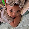 baby, child, infant, headband, bow, curly_hair, blanket, quilted, lying_down, cute, soft_lighting, indoors, clothing, person, portrait, face, expression, sleepwear, toddler, small