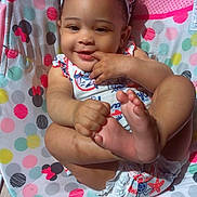 Jazmone is registered to the contest to win money with this photo: baby, child, smiling, cute, headband, foot, hand, sitting, colorful, patterned, polka_dot, mickey_mouse, pink, white, clothing, indoor, seat, wood_floor, playful, happy