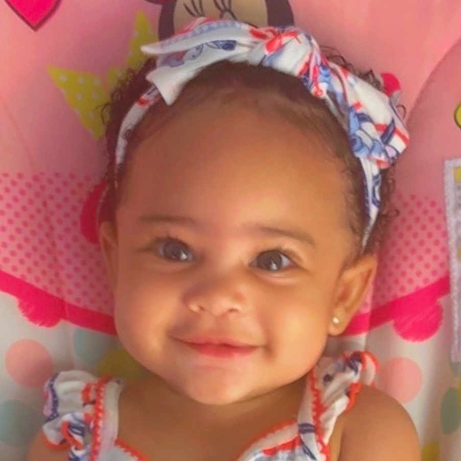 Jazmone is registered to the contest to win money with this photo: toddler, child, smiling, headband, curly_hair, cute, portrait, baby, face, pink_background, clothing, earrings, happy, indoor, colorful, pattern, closeup, person, youth, infant