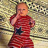 Kolte joined the competition — help win amazing prizes! baby, baby_clothes, blanket, child, curious, cute, floor, hands, indoors, infant, lying_down, newborn, patterned_blanket, person, portrait, red_clothing, socks, star_pattern, striped_outfit, young