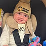 baby, child, car_seat, hat, pom_pom, mickey_mouse, beige, plush_toy, toy, smiling, safety_harness, clothing, cute, indoor, person, infant, seatbelt, hand, face, happy