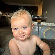 Harlen is registered to the contest to win money with this photo: toddler, child, blonde_hair, blue_eyes, smiling, shirtless, indoor, kitchen, playpen, baby, face, person, cute, young_child, home, portrait, happy, skin, expression, blurry_background