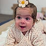 Nëyla participe au concours pour gagner de l'argent avec cette photo : baby, child, smiling, flower_hair_clip, cute, infant, happy, face, eyes, clothing, blanket, indoors, portrait, skin, hand, lying_down, soft_texture, curly_hair, closeup, young