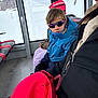 child, kid, sunglasses, blue_jacket, scarf, gloves, backpack, snow, mountains, gondola, cabin, window, seat, adult, winter_clothing, portrait, travel, reflection, ski_trip, pink_bag