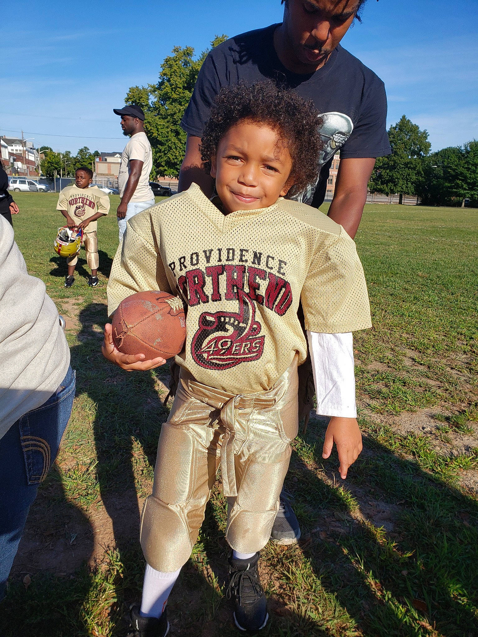 Bernard is registered to the contest to win money with this photo: american_football, child, community, fun, grass, headwear, joy, person, photography, recreation, style, t_shirt, team, tree, youth